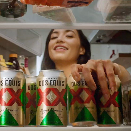 photo d'une femme qui sort une bière Dos Equis du réfrigérateur